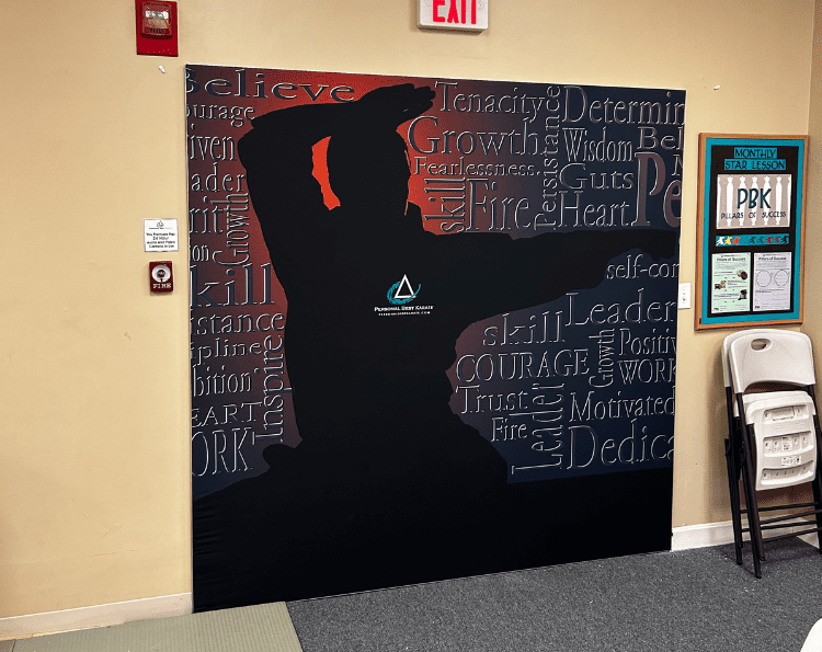 image displays a motivational mural featuring a silhouetted figure in a dynamic pose, set against a backdrop of inspiring words such as "Believe," "Tenacity," "Growth," "Courage," and "Leadership".